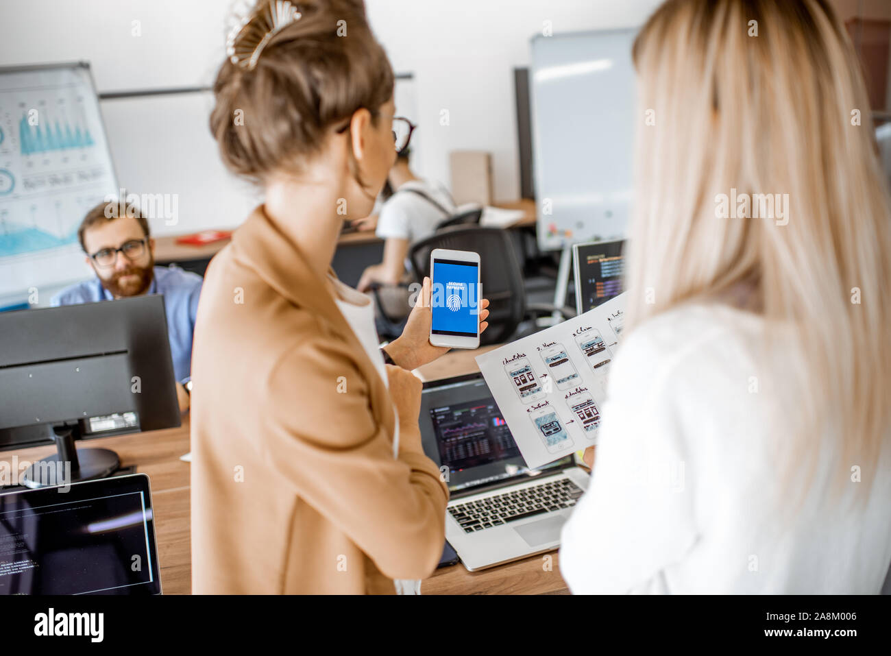 Developers or web designers developing mobile application for banking in the office, close-up on phone and paper sketches Stock Photo