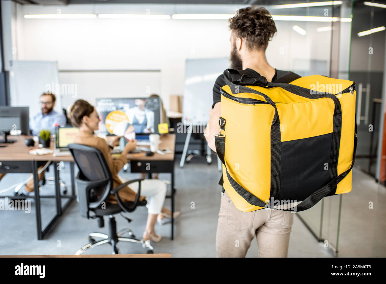 Courier delivering products for office workers, carrying yellow thermal