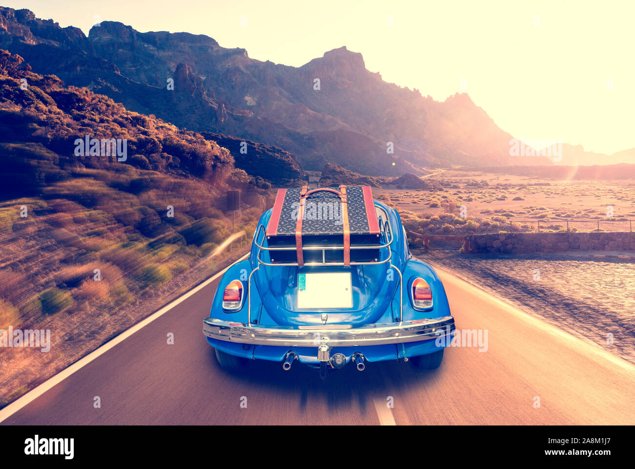 Retro car with luggage on the roof rack on the mountain road. Travel ...