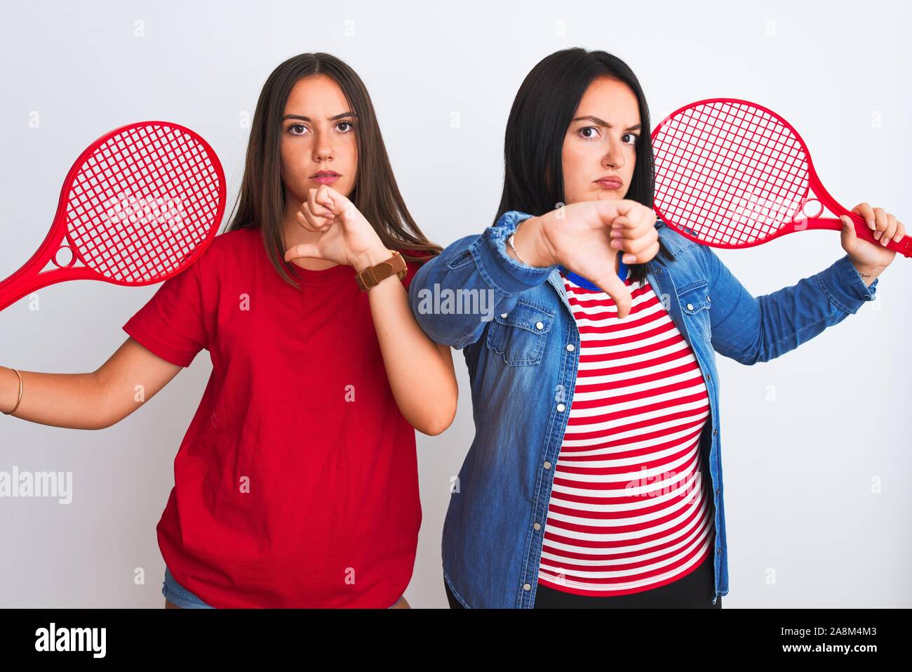 Young beautiful sportswomen holding tennis racket standing over ...