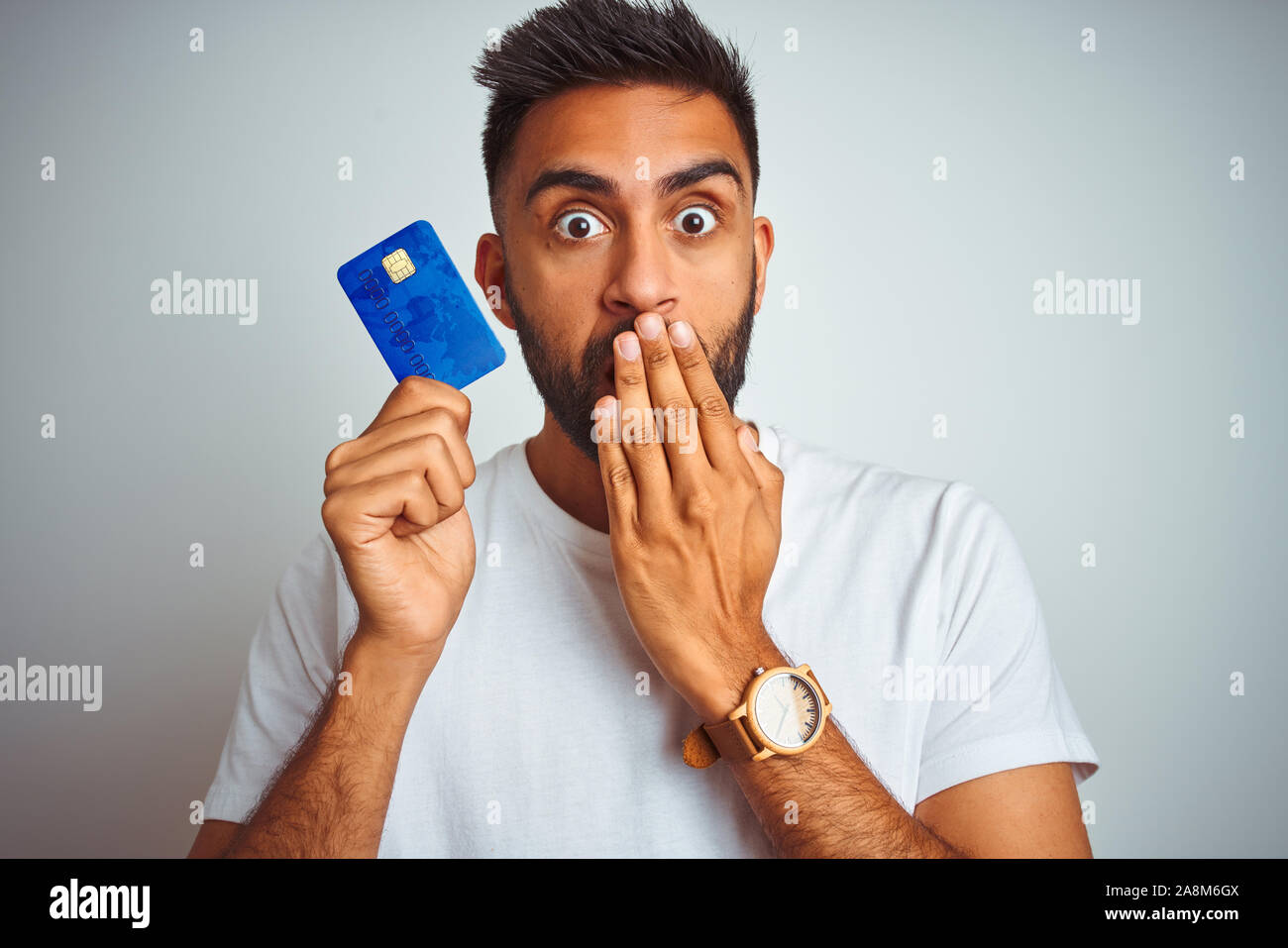 Young indian customer man holding credit card standing over isolated ...