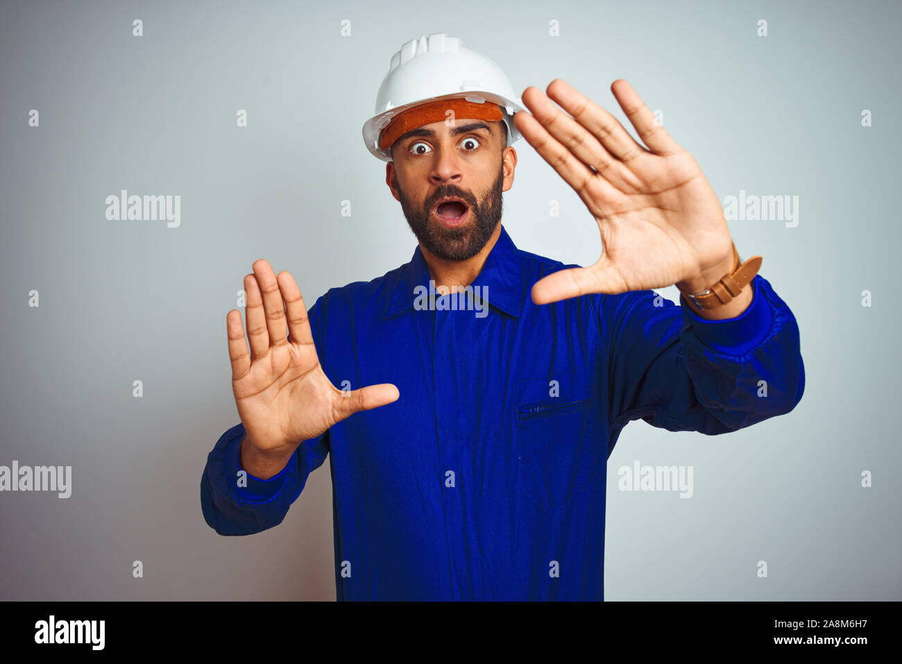 Handsome indian worker man wearing uniform and helmet over isolated ...