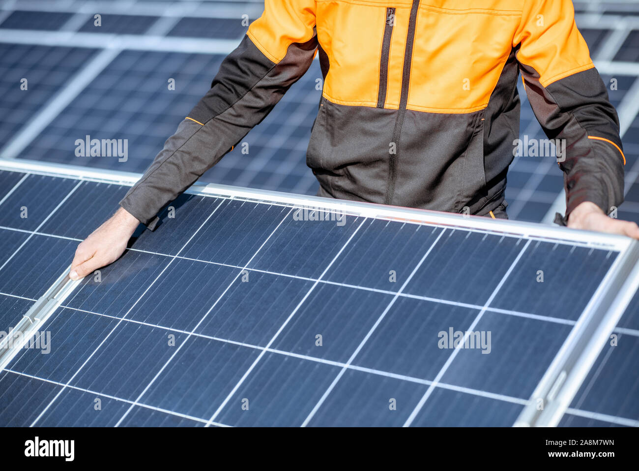 Workman installing or replacing solar panel on a photovoltaic rooftop plant, close-up Concept of maintenance and installation of solar stations Stock Photo