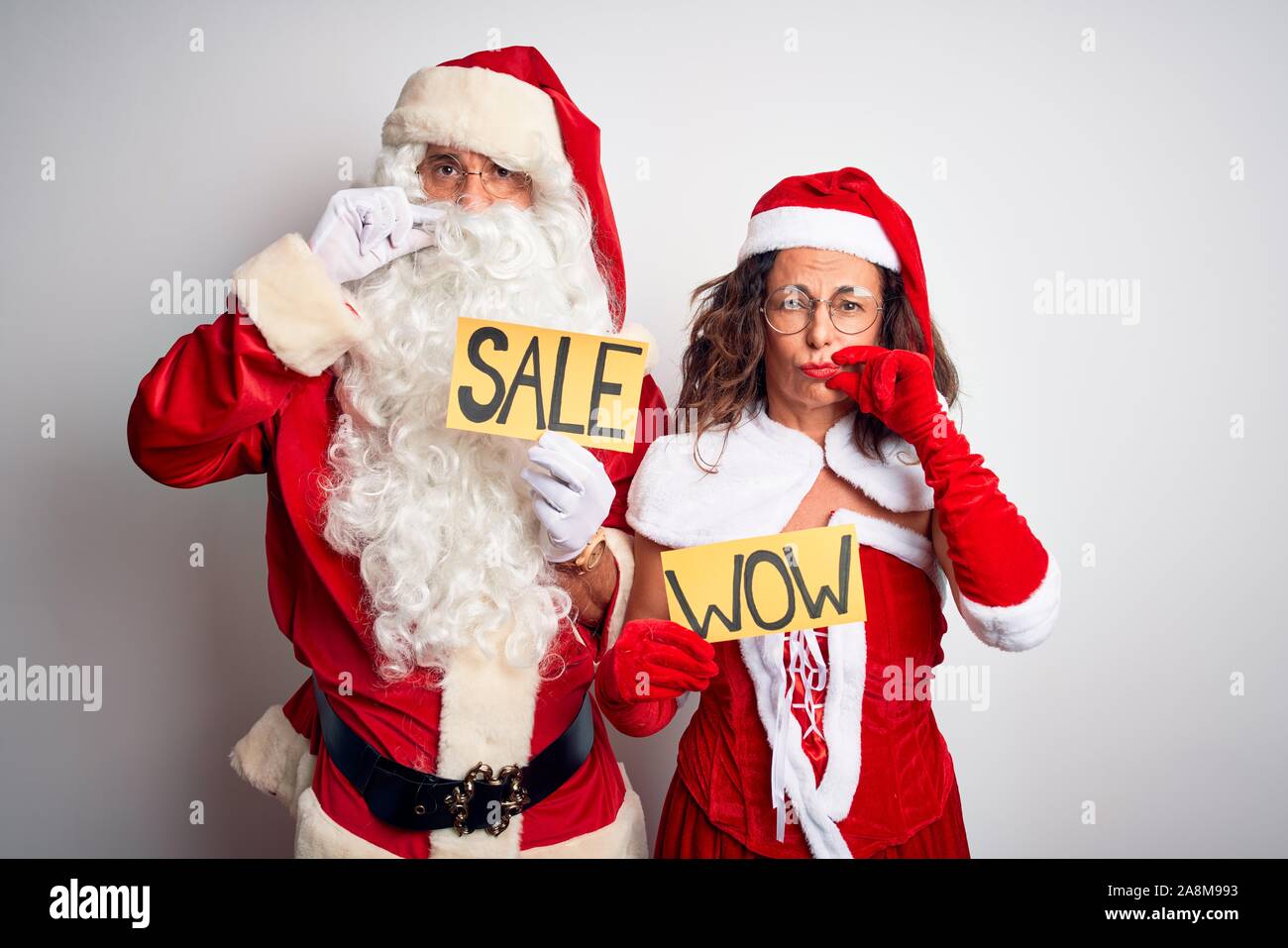 Couple Wearing Santa Costume Holding Wow And Sale Banner Over