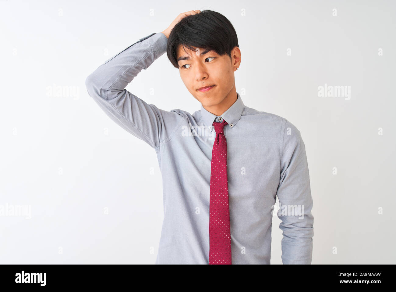 Chinese businessman wearing elegant tie standing over isolated white background confuse and wondering about question. Uncertain with doubt, thinking w Stock Photo