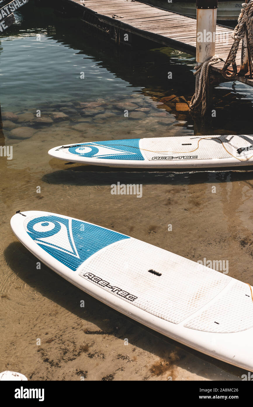 Detail shot of stand up paddleboards (SUP) on the river's edge near the Dunbogan Boat Shed and Marina on a sunny day. Stock Photo