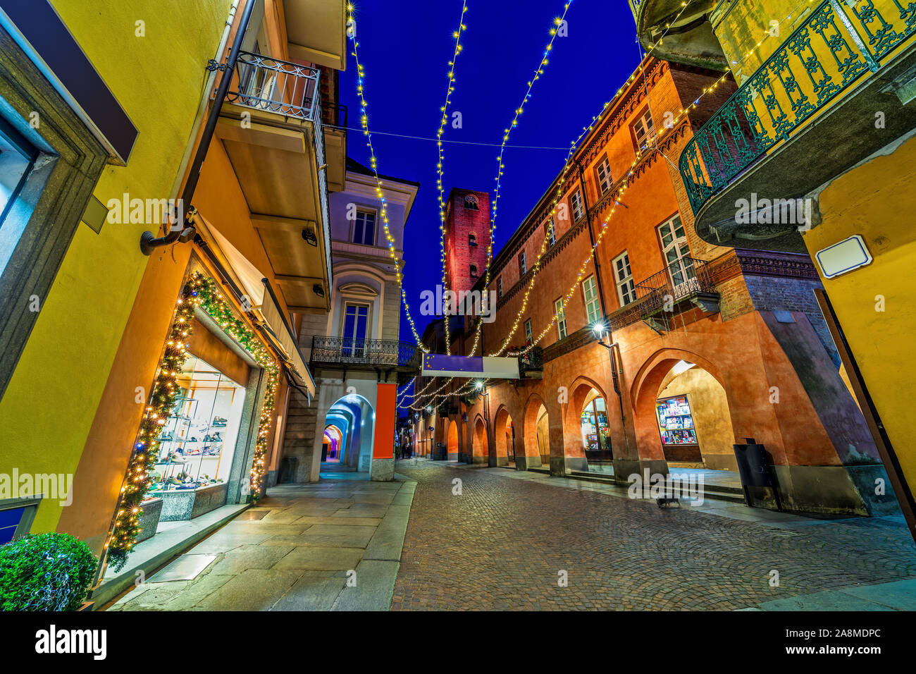 Cobblestone pedestrian street with Christmas illumination in old town of Alba in Piedmont, Northern Italy. Stock Photo