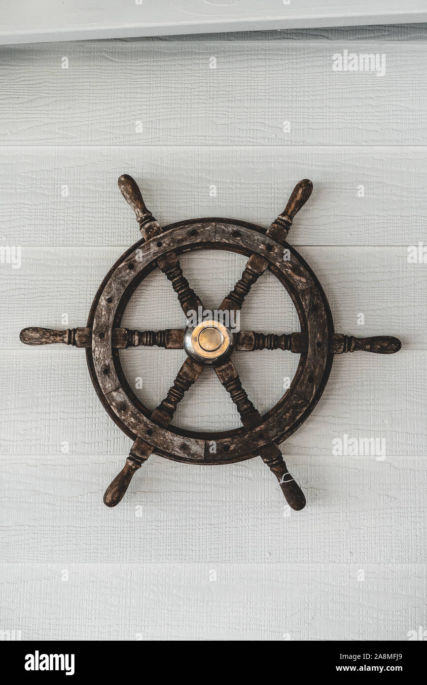 Sailors wooden boat steering wheel (helm) on a white wall. Nautical decoration. Stock Photo