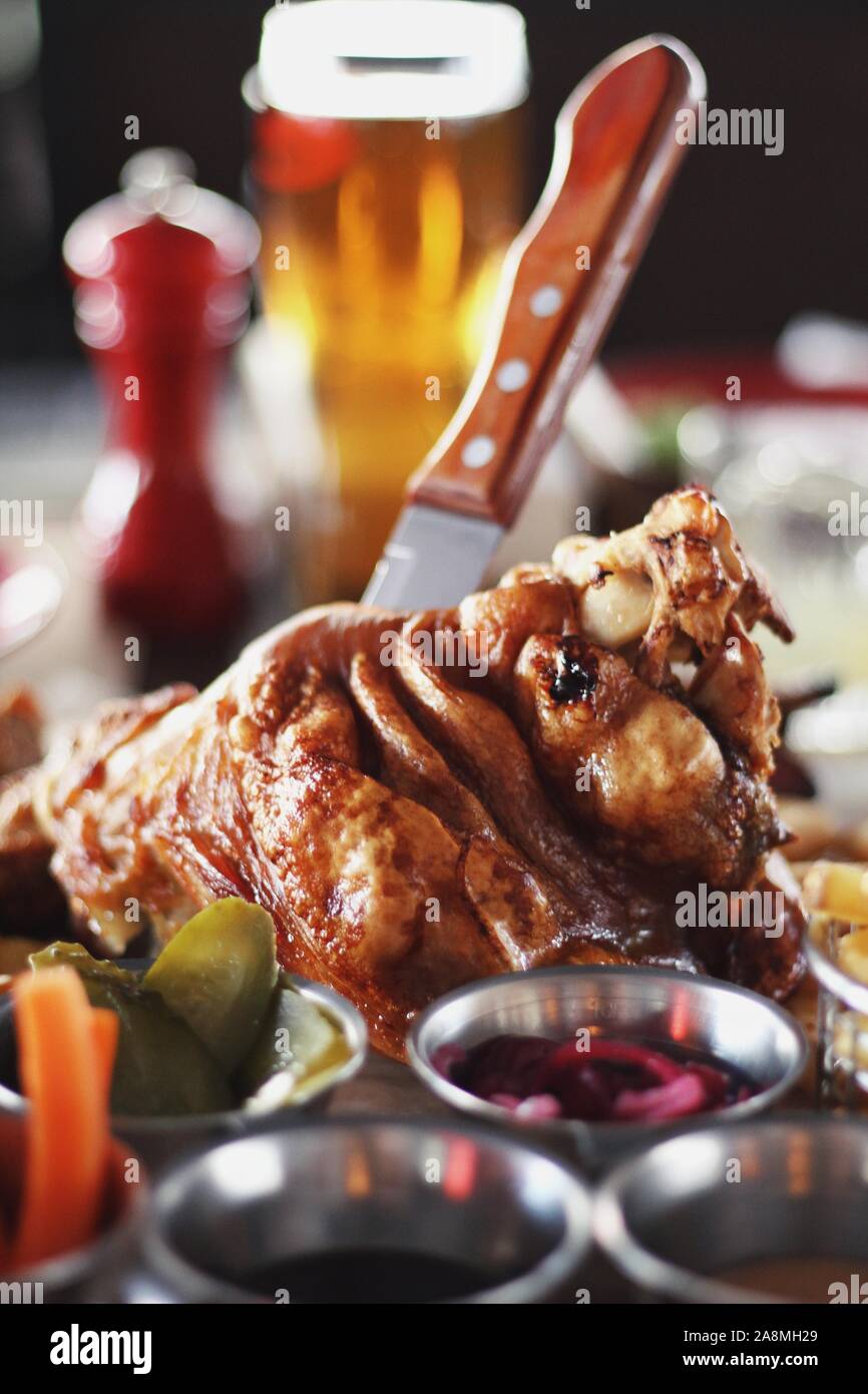 Pork knuckle with carrot, cucumber, sauce and light filtered beer on