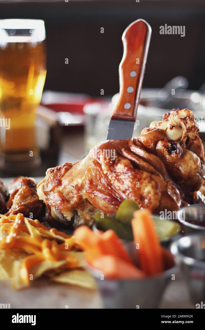 Pork knuckle with carrot, cucumber, sauce and light filtered beer on