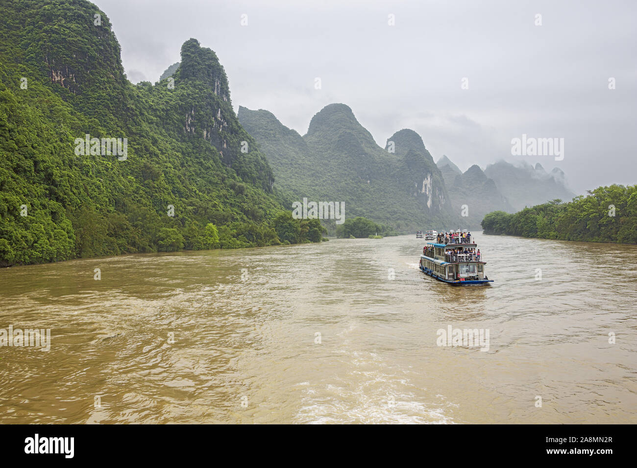 Editorial: GUILIN, GUANGXI, CHINA, April 19, 2019 - River cruise boats navigating in convoy on the Li River near Guilin Stock Photo