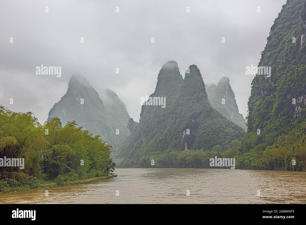 Steep hills bordering the Li River pointing to the clouds in the vicinity of Yangshuo near Guilin Stock Photo