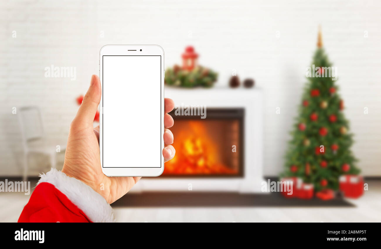 Download Modenr White Hone In Santa Claus Hand With Isolated Screen For Mockup Fireplace And Christmas Tree In Background Stock Photo Alamy