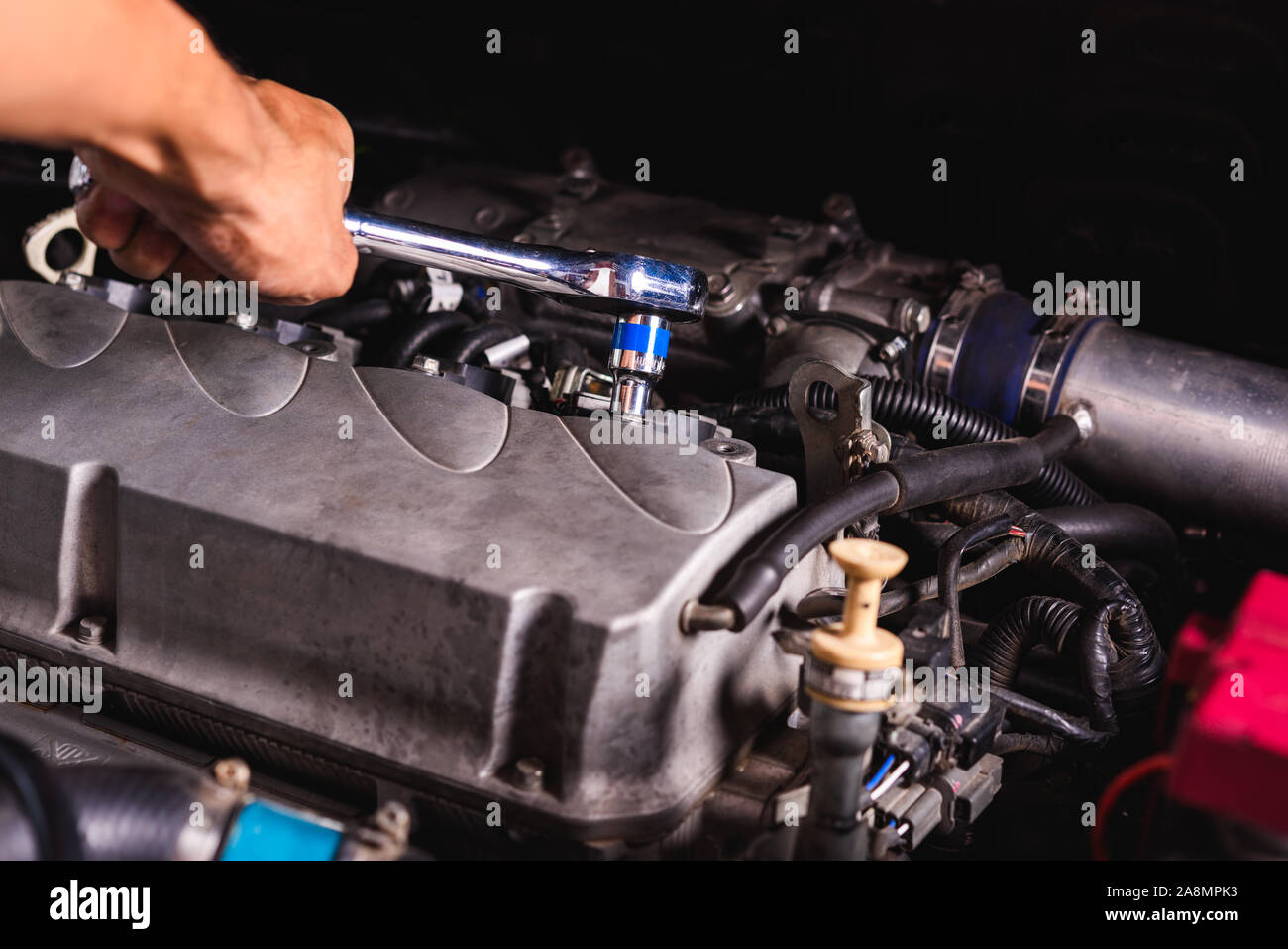 Hand of auto mechanic technician service engine and using wrench socket ...