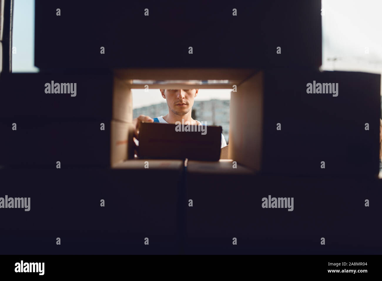 Deliveryman looking through a crack in the boxes Stock Photo - Alamy