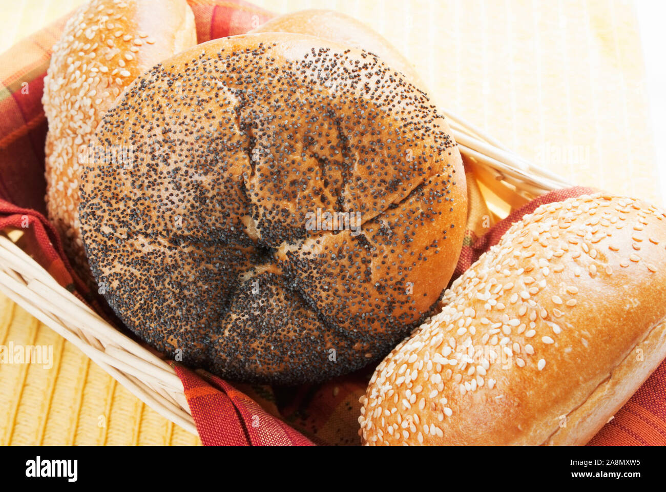 Poppy seed and sesame seed Kaiser Rolls in a light colored wood basket