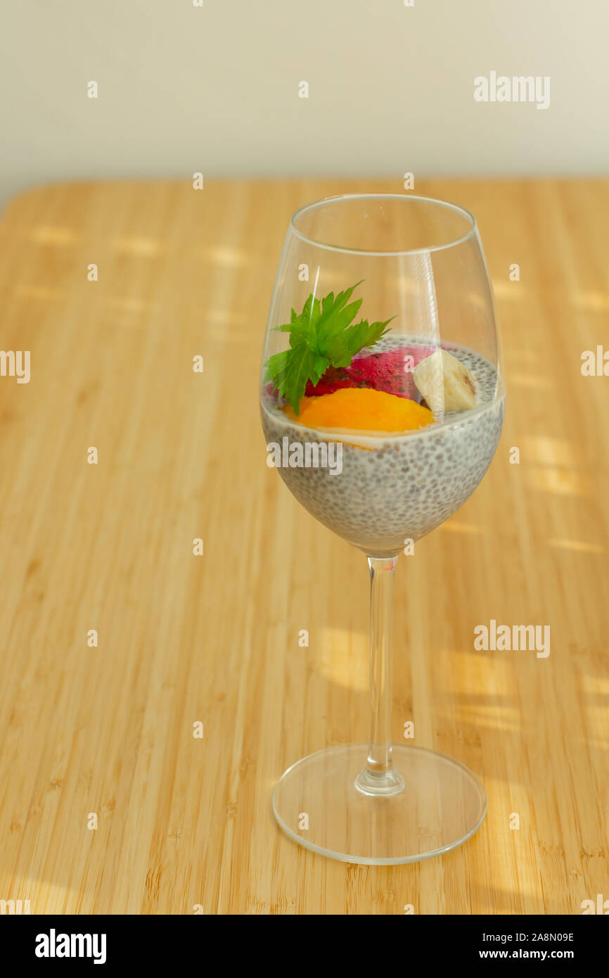 Glass of chia healthy food coconut pudding with banana, mango and dragon fruit on the bamboo background. Healthy concept Stock Photo
