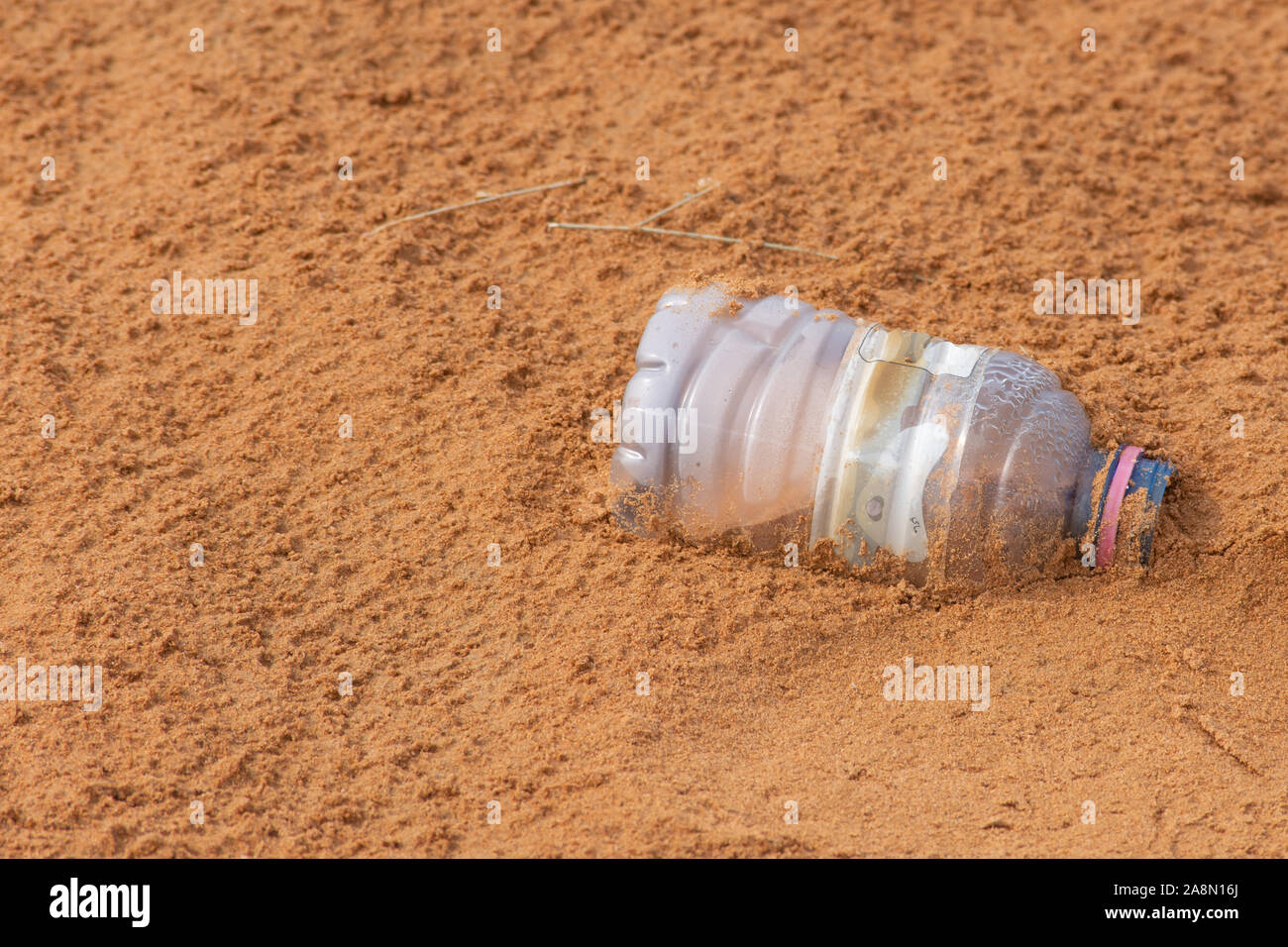 Plastic pollution in the desert sand. Need for awareness of enviornmental protection, recycling, and protecting the world. Environmental concept copy Stock Photo