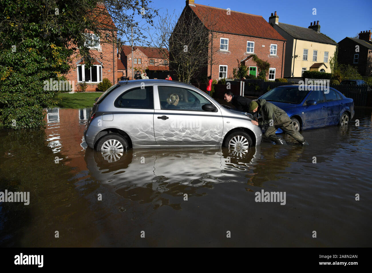 Residents attempt to push a stranded car out of floodwater in Fishlake, Doncaster as parts of England endured a month's worth of rain in 24 hours, with scores of people rescued or forced to evacuate their homes. Stock Photo