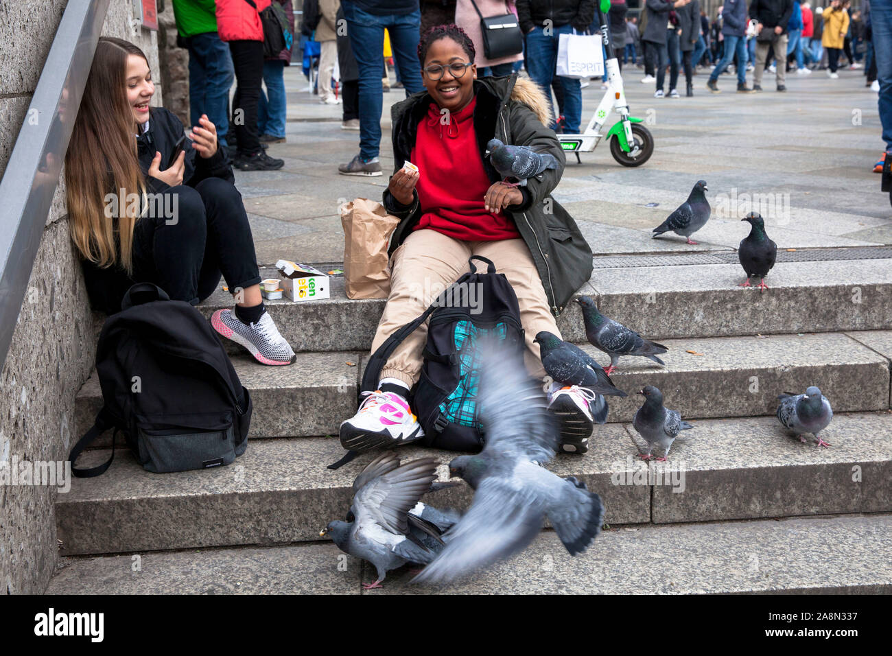 young women feeding feral pigeons in front of the cathedral, Cologne, Germany.  junge Frauen fuettern Stadttauben vor dem Dom, Koeln, Deutschland. Stock Photo