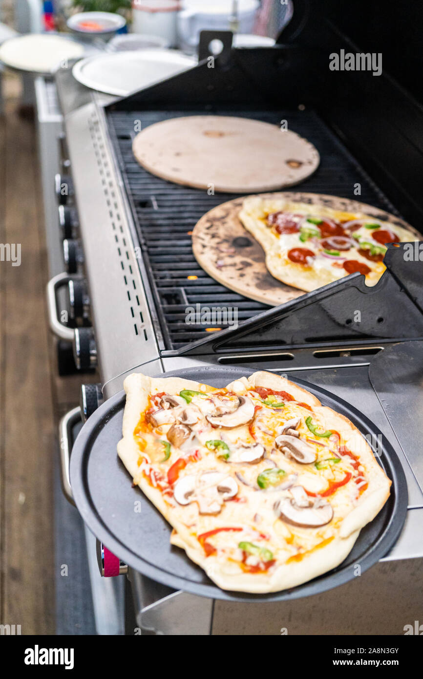 Preparing individual grilled pizzas on an outdoor gas grill Stock ...