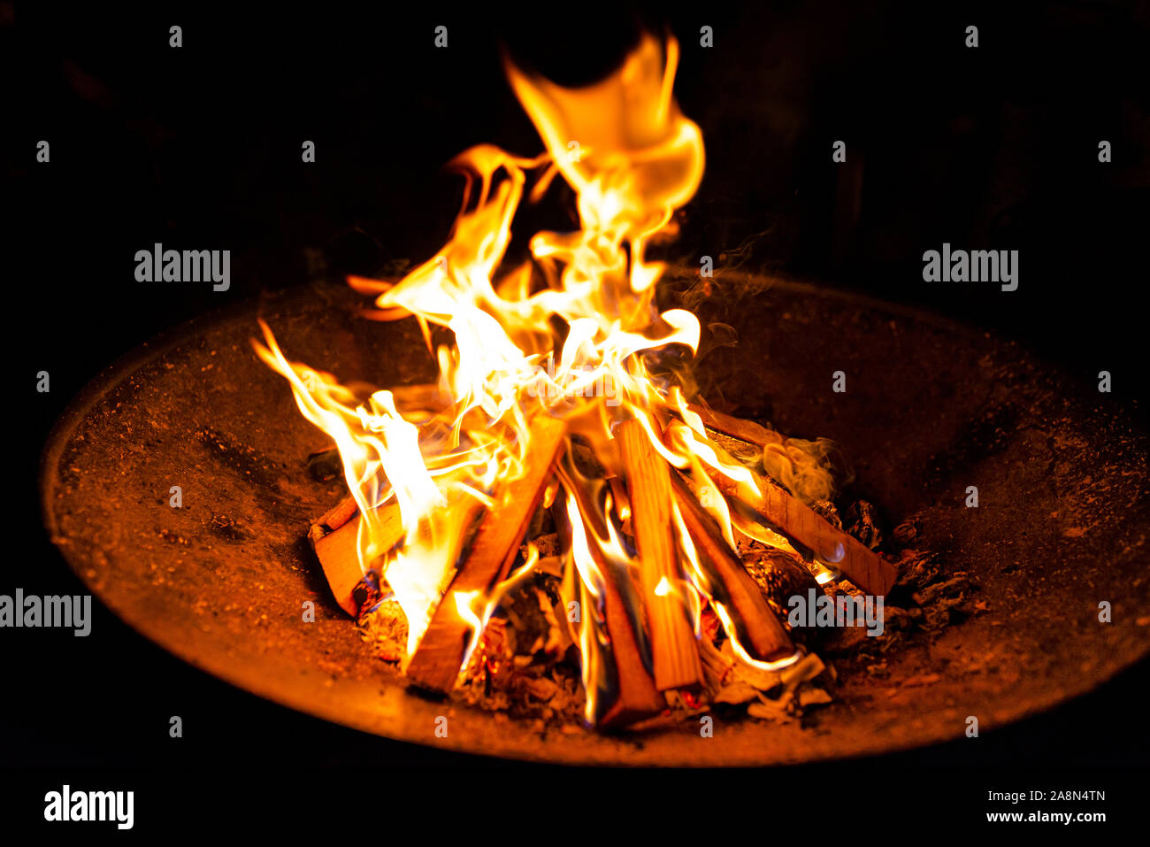 High flames from a burning wood fire on a metal grate at night Stock ...