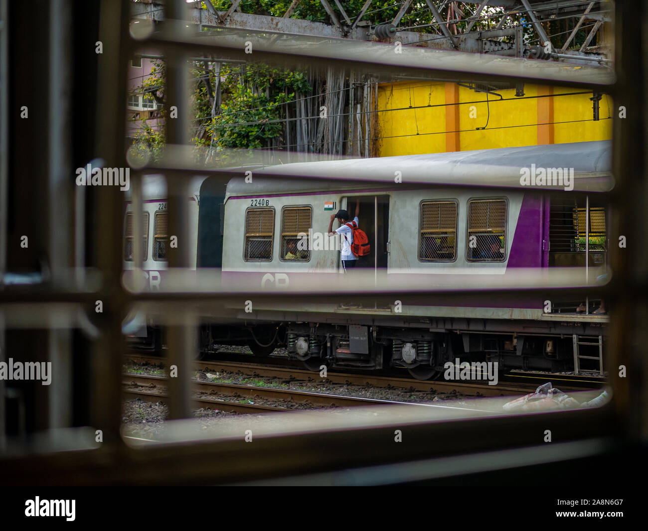 Mumbai, India - October 28,2019 : Unidentified passengers standing on the doors of running local train during rush hours Stock Photo