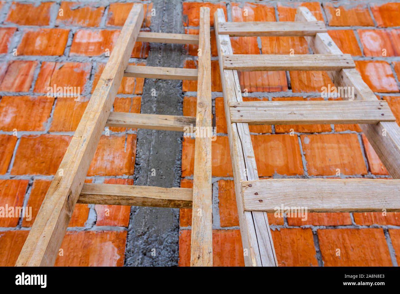 Front view on used wooden ladders, leaning against the wall for access