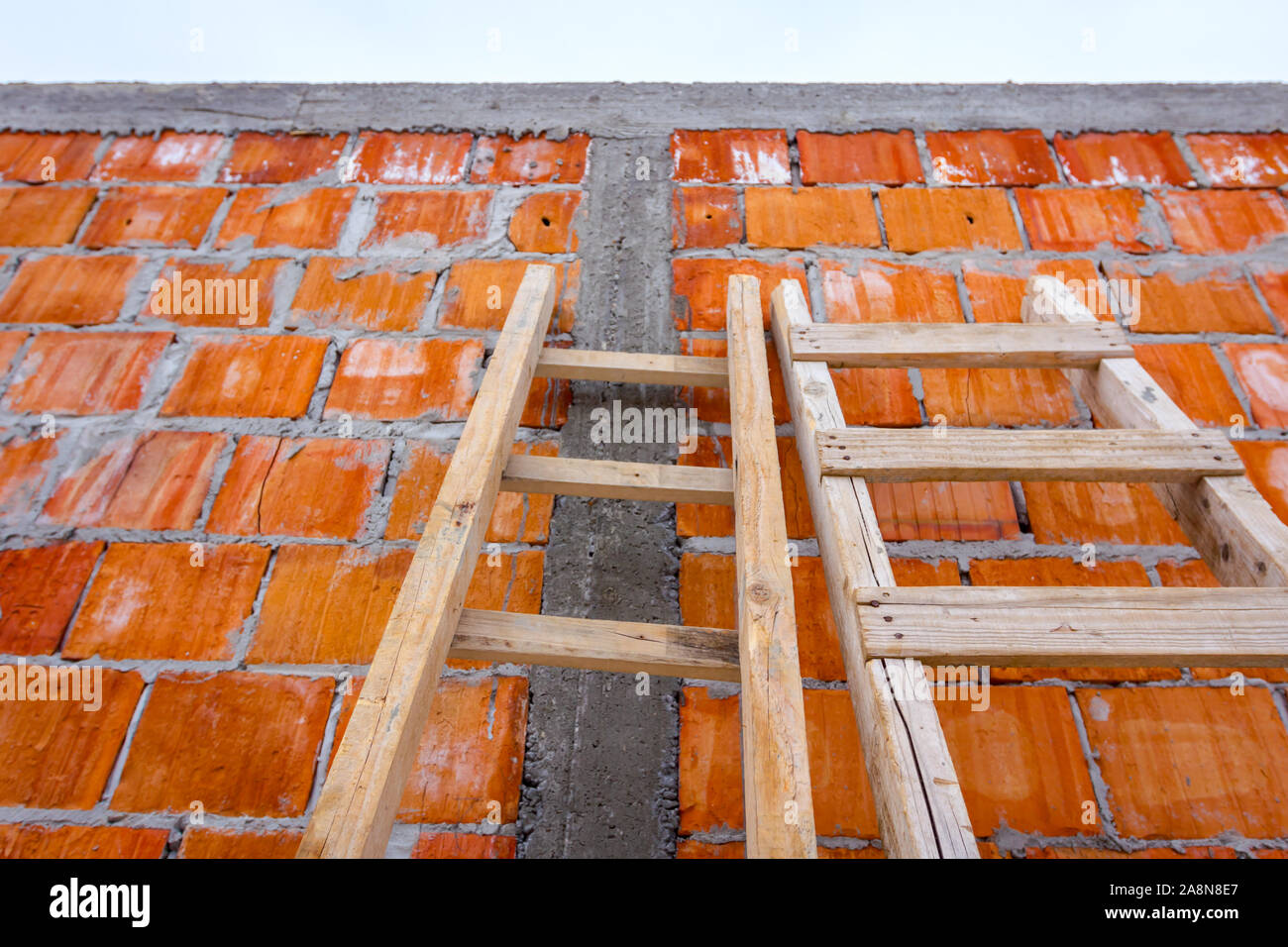 Front view on used wooden ladders, leaning against the wall for access