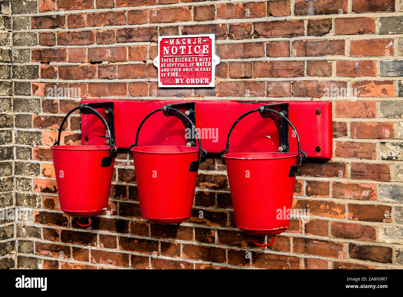Three fire buckets hanging on the wall. Stock Photo