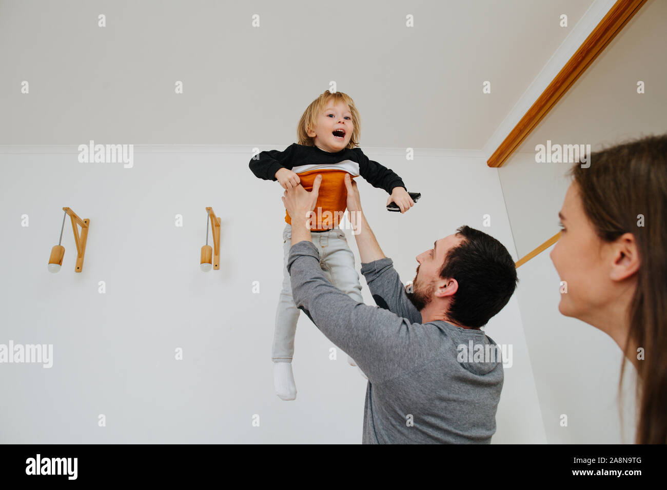 Happy young family moving to a new home, father throwing kid in the air