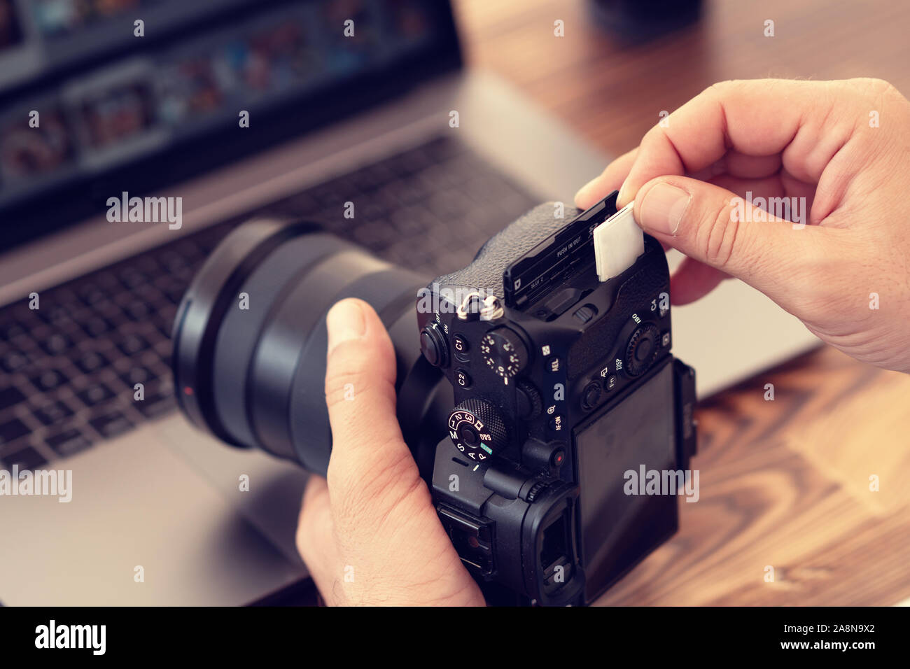 Photographer inserting or removing a memory card in professional camera. Stock Photo
