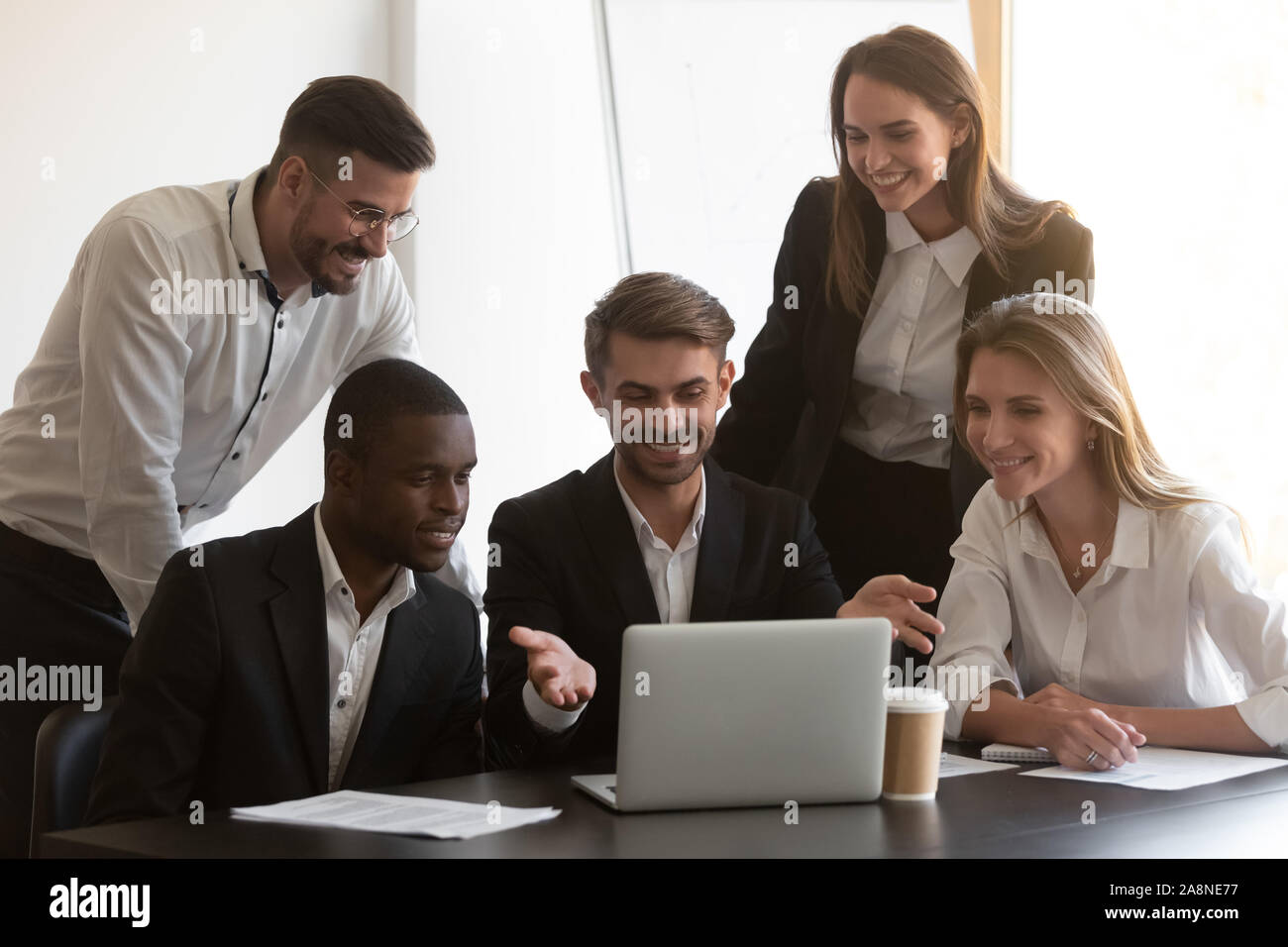 Smiling diverse employees cooperating in office using laptop Stock Photo