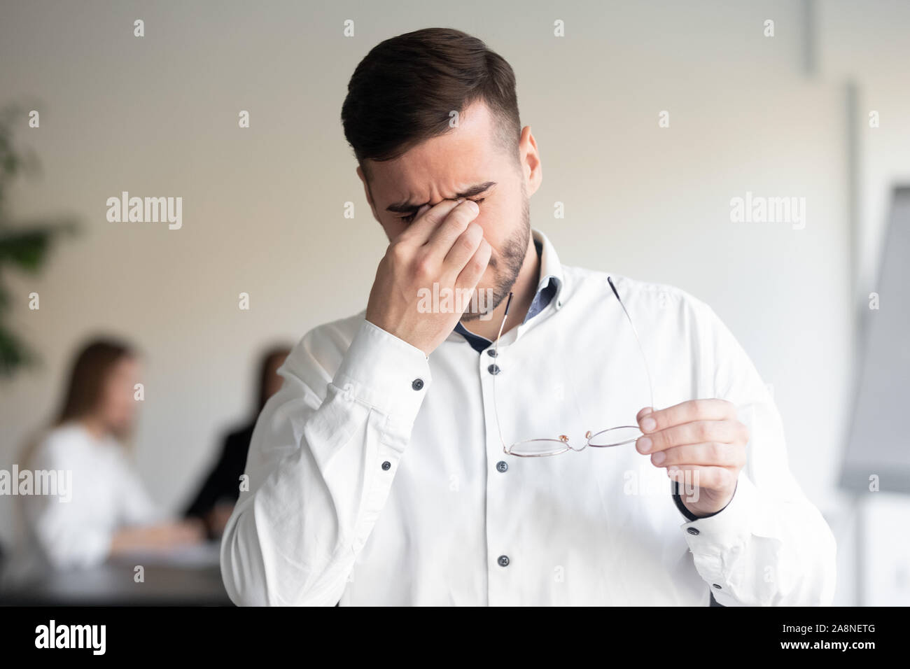 Tired male employee take off glasses suffering from headache Stock Photo