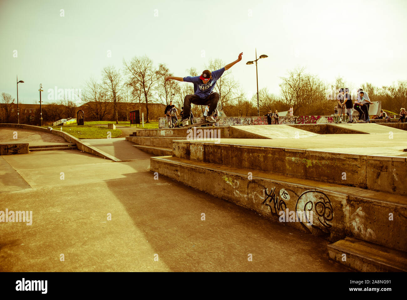 A skateboarder Ollie's off a very high double step at the skate park