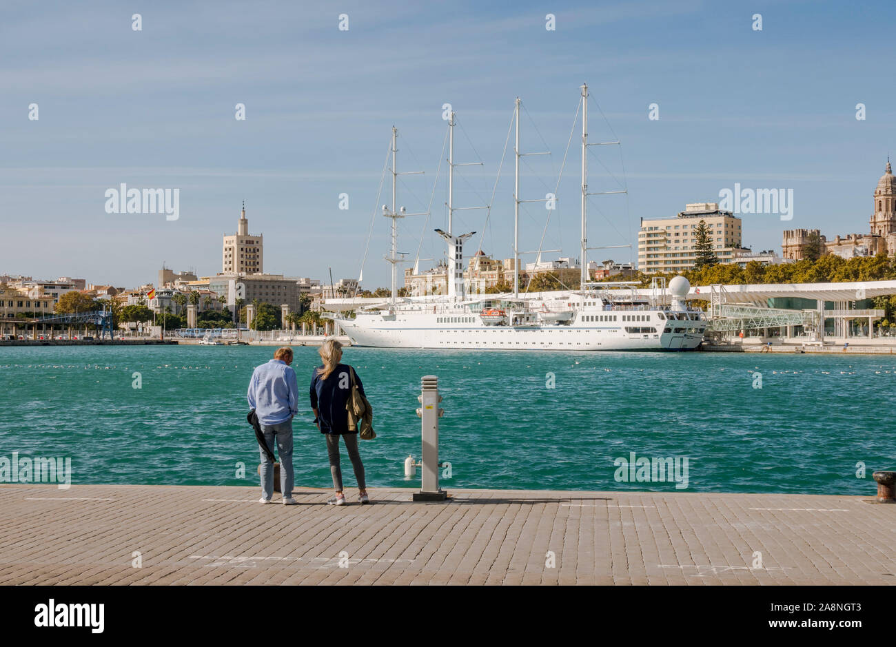 Couple watching the four masted cruise ship MSY Wind Star, moored in port of Malaga, Andalusia, Spain Stock Photo