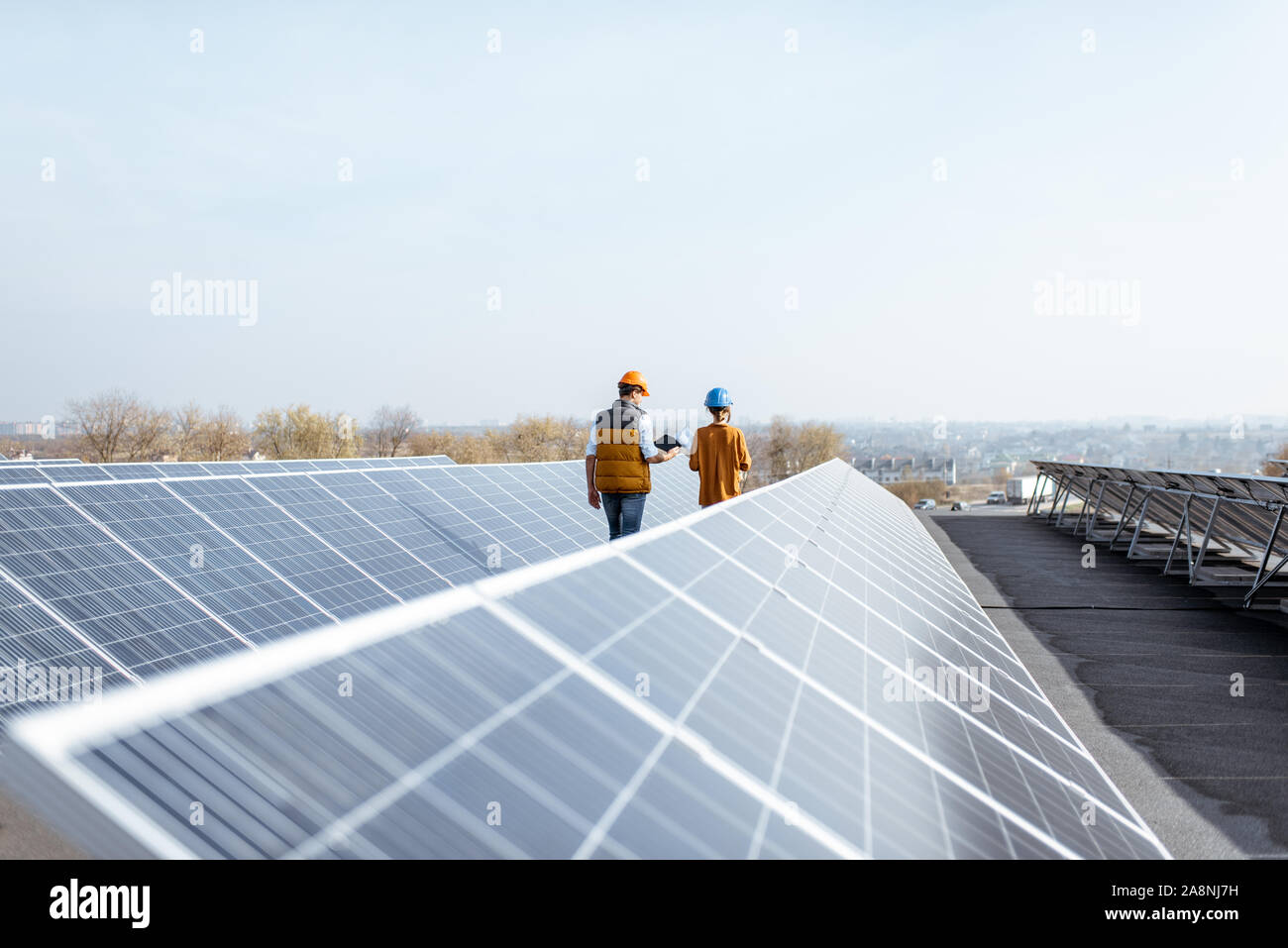 View on the rooftop solar power plant with two engineers walking and ...