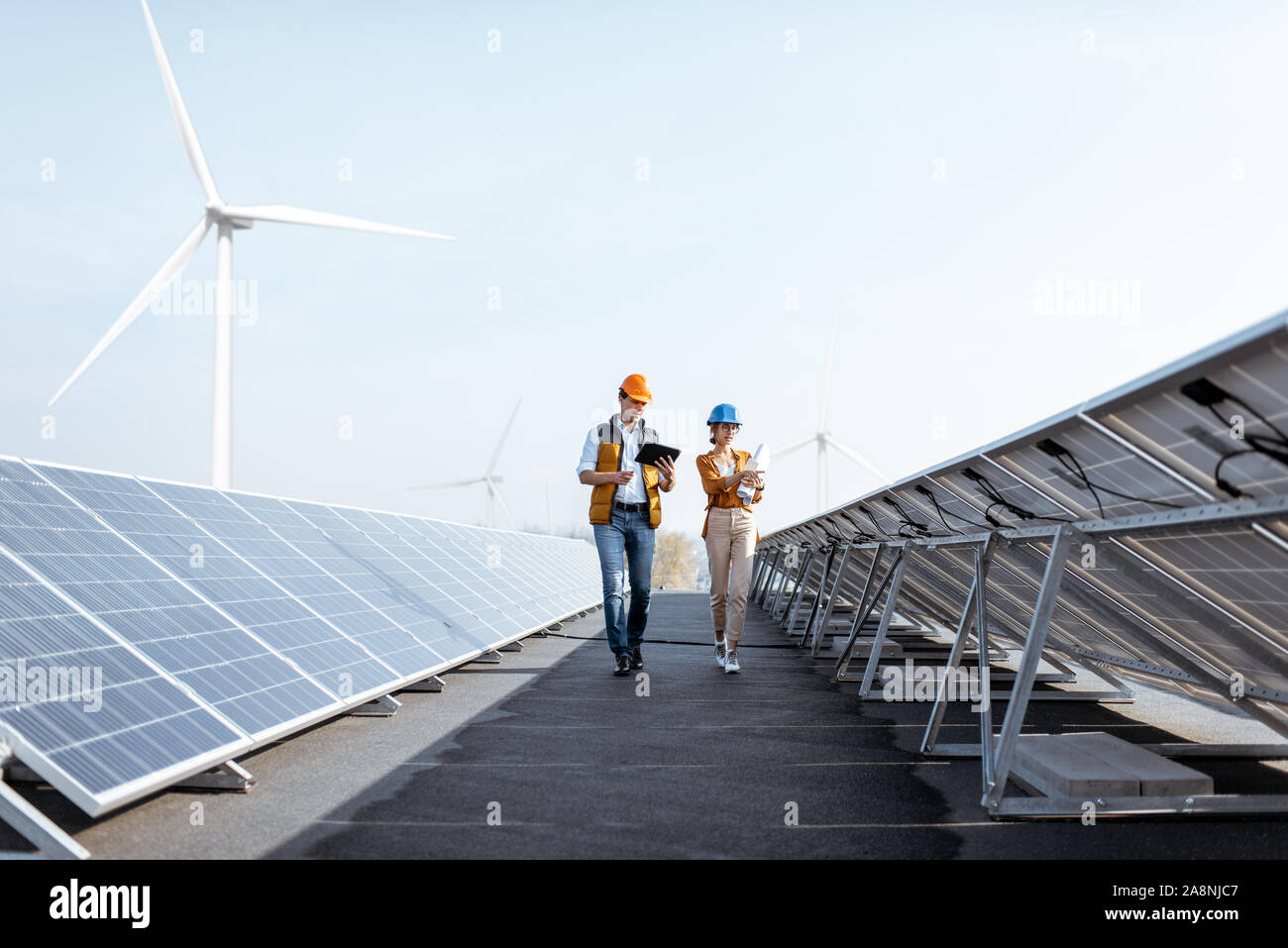 View on the rooftop solar power plant with two engineers walking and ...
