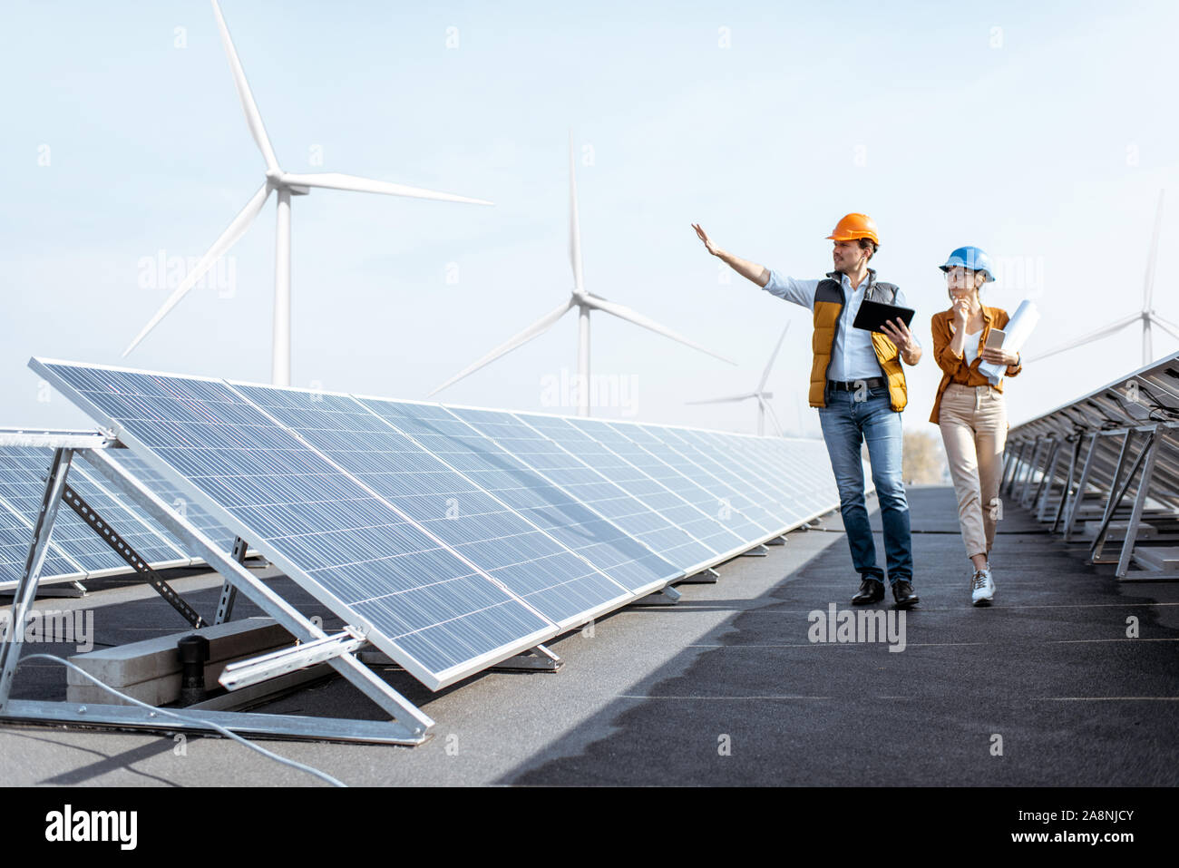 View on the rooftop solar power plant with two engineers walking and ...