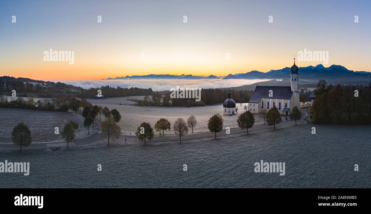 Beautiful foggy autumn morning in Bavaria - aerial view of Wilparting Church before Alps in Chiemgau Stock Photo