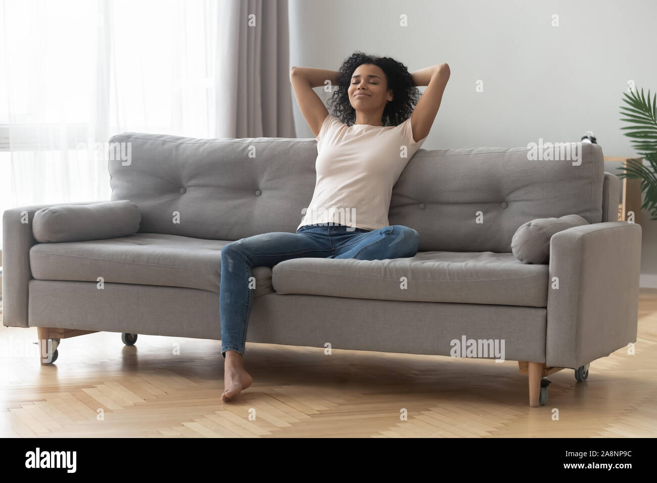 Satisfied African American woman with closed eyes relaxing on couch ...