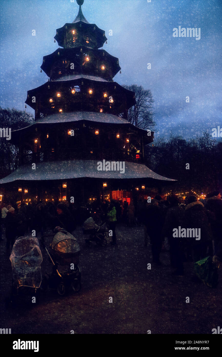 Munich, Germany - Christmas market at Chinese Tower in Englischer Garten at night with snowfall Stock Photo