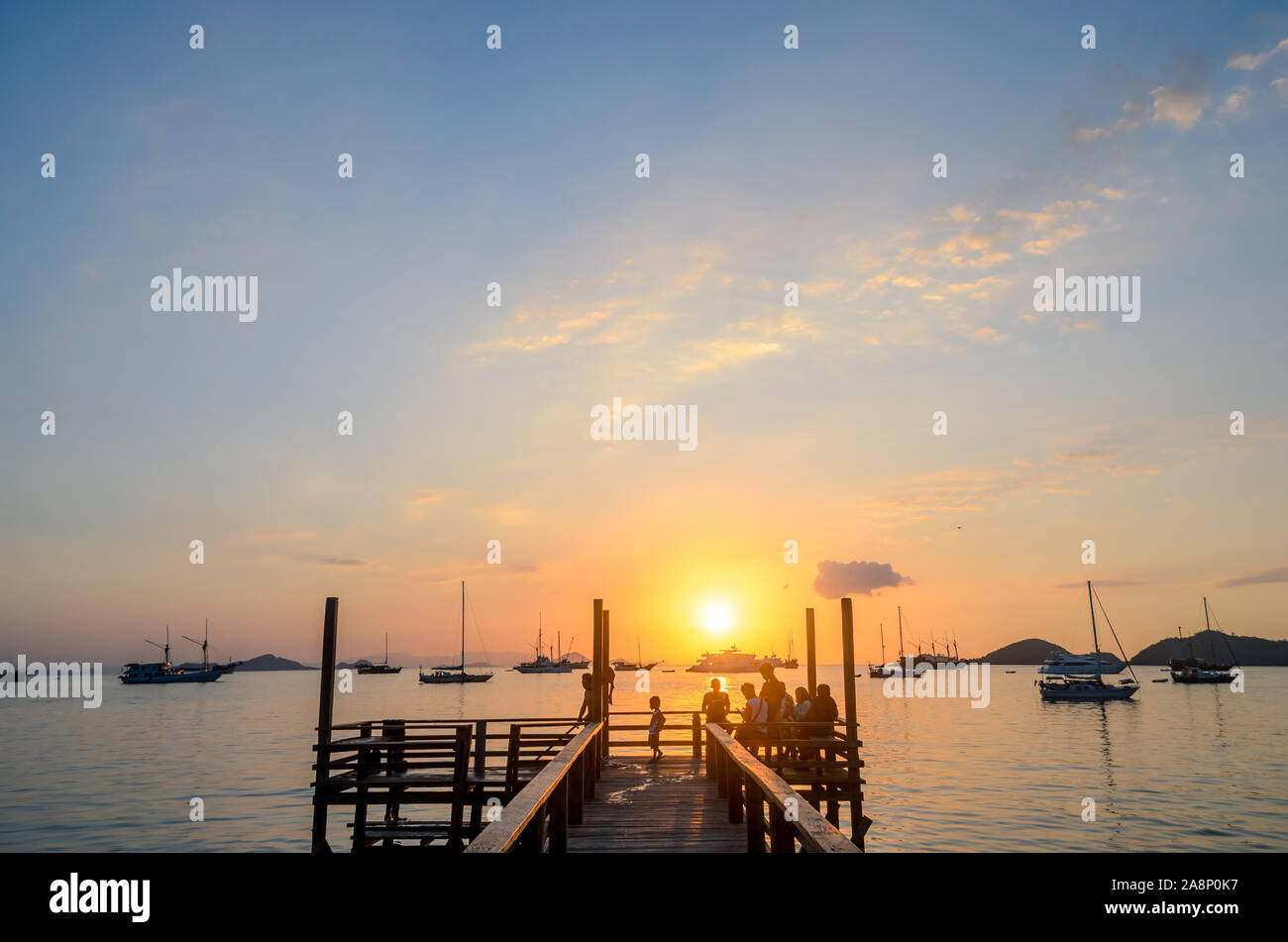 Tourists enjoy the sunset at the wooden pier beach, on Labuan Bajo, West Manggarai, Flores Island, East Nusa Tenggara, Indonesia Stock Photo