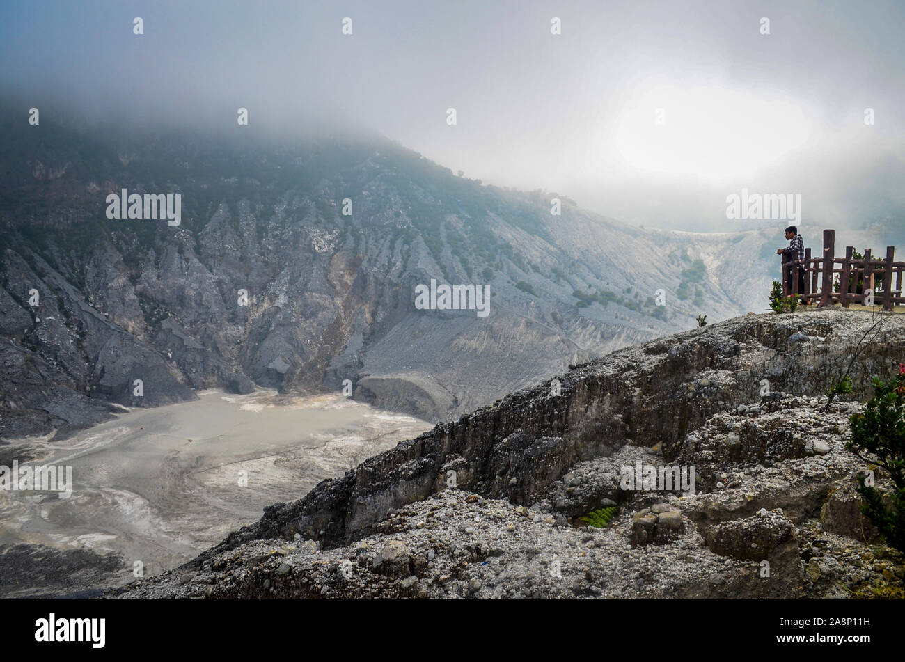 A young man standing on the crater rim, at Mount Tangkuban Perahu, Bandung, West Java, Indonesia Stock Photo