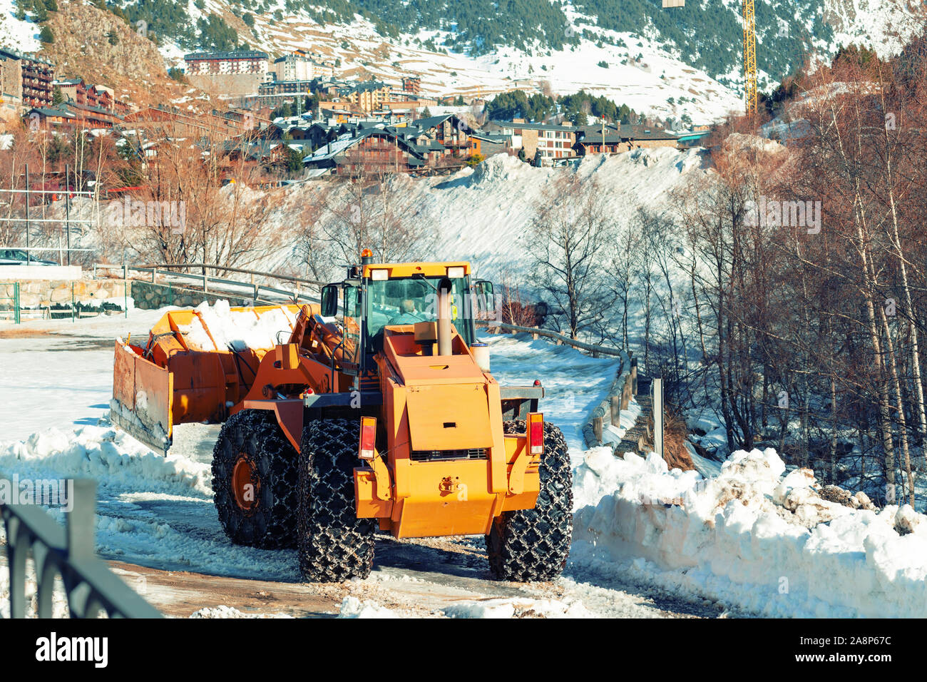 A bulldozer with chains on wheels removes snow in a village in the
