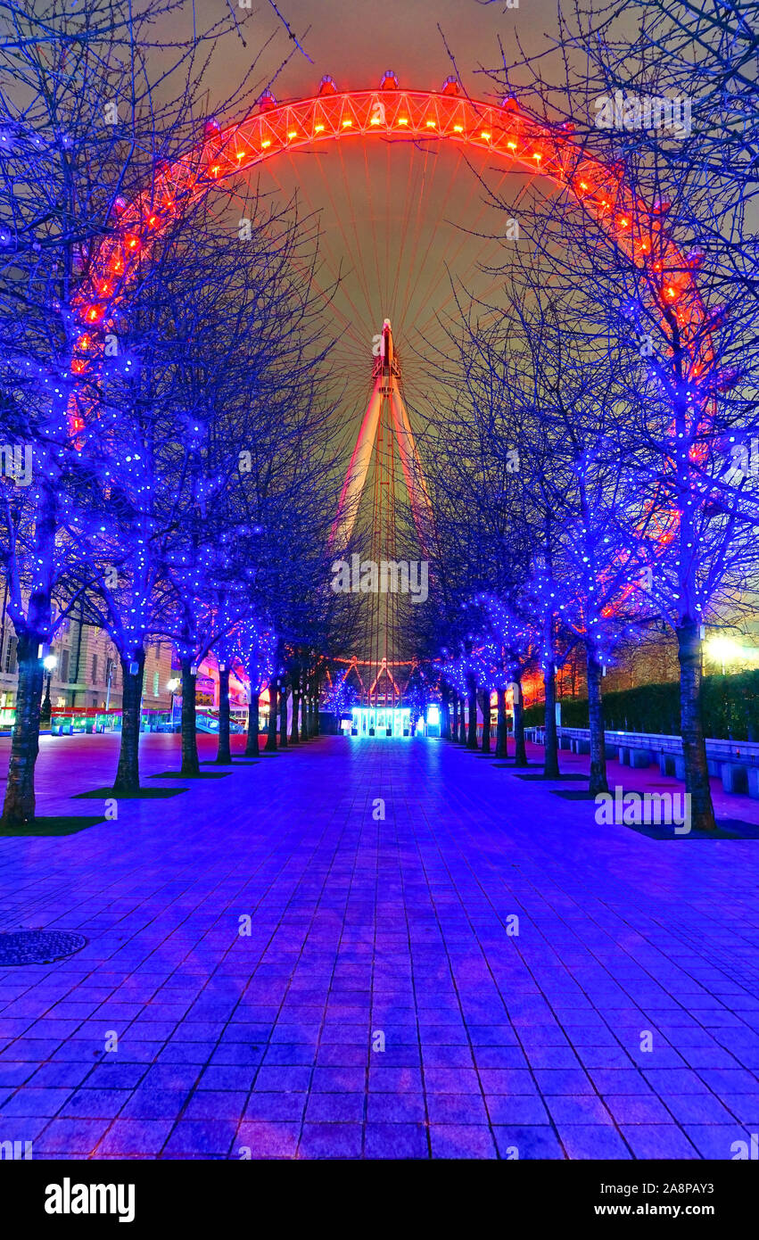 View of London Eye with aligned trees at night in London Stock Photo