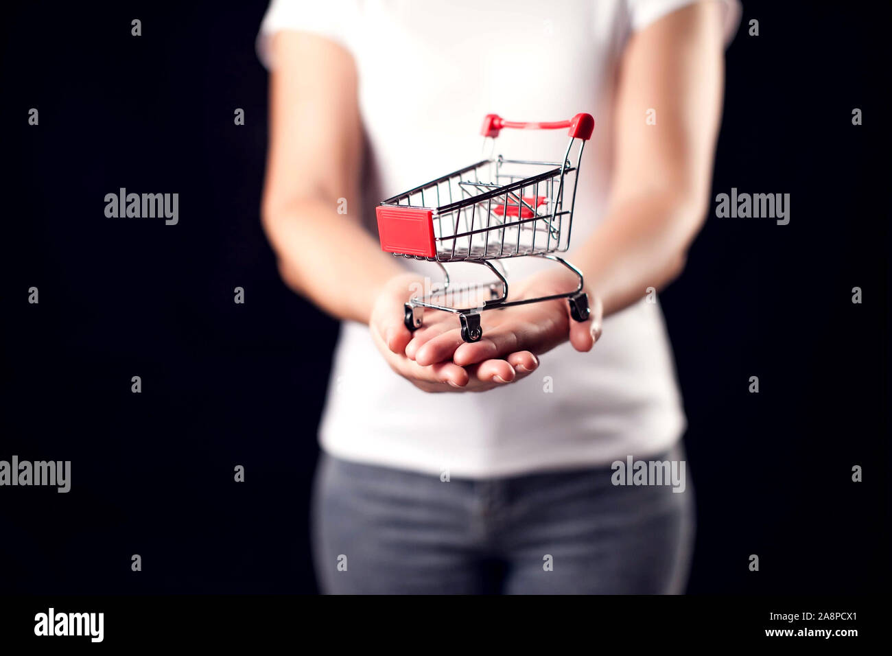 Woman holds toy shopping trolley. People and shopping concept Stock Photo