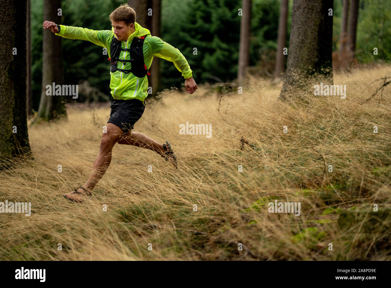 A young athlete in barefoot shoes runs down the mountain. Mountain run
