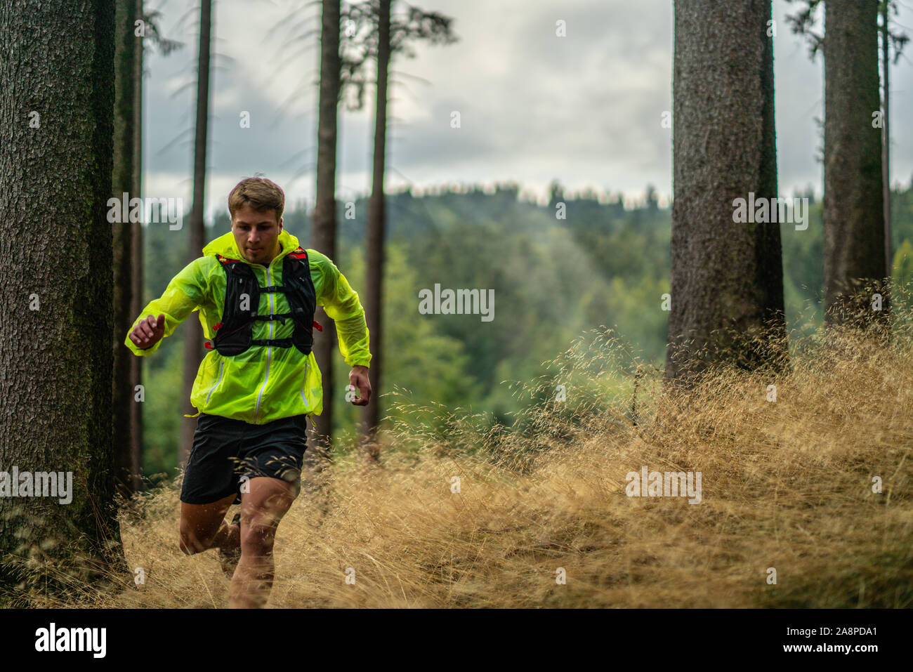 A young athlete in barefoot shoes runs down the mountain. Mountain run