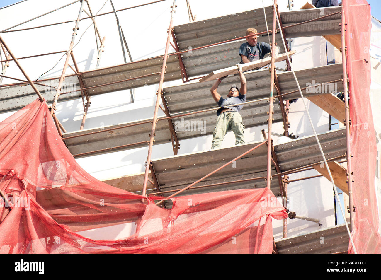 Belgrade, Serbia - October 25, 2019: Two unprotected construction workers on the scaffold during building facade reconstruction, an unsafe, hazard  an Stock Photo